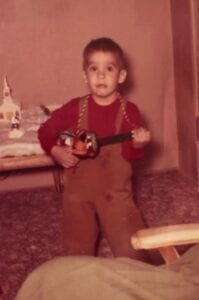 A young boy holding a toy chain saw.