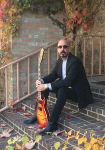 A man sitting on steps with his guitar.