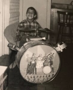 A young boy sitting on top of a drum.