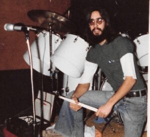 A man with long hair and beard holding a drum.