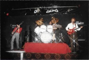 A band playing on stage with red and white instruments.