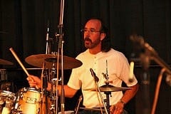 A man playing drums in front of other people.